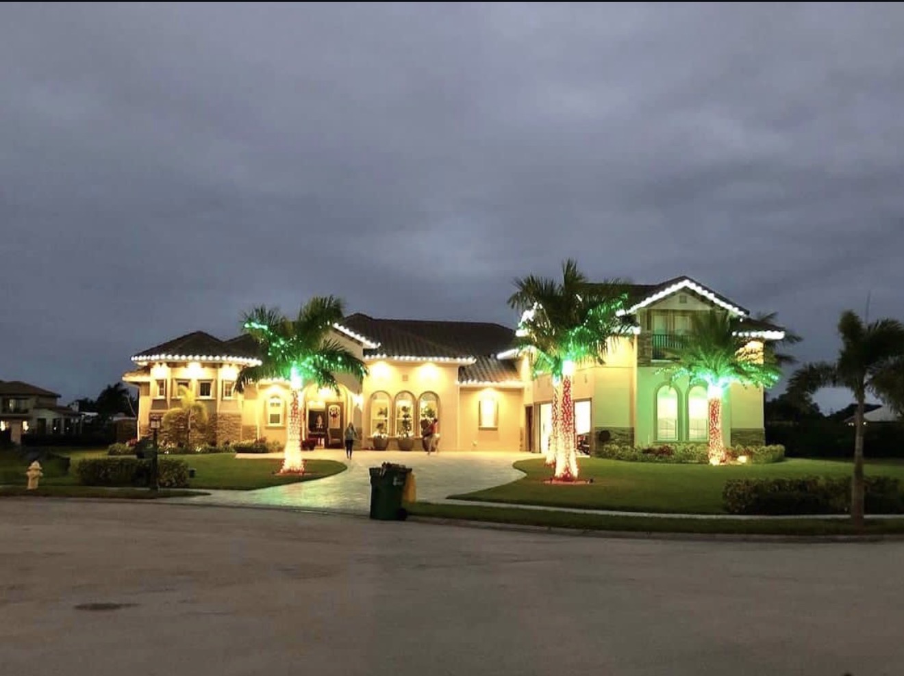 Florida home with white roofline lights and festive illuminated palms