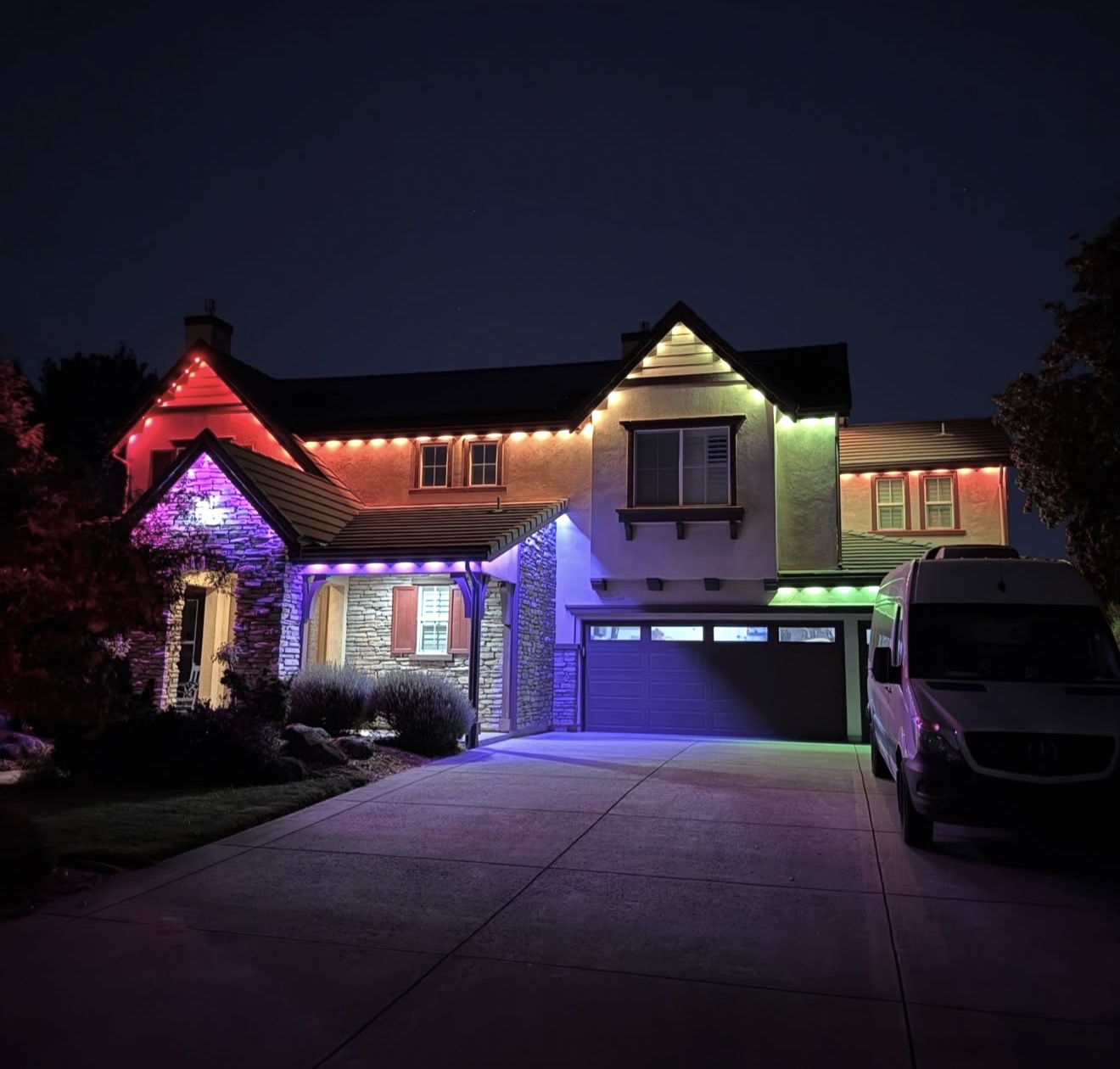 Two-story home with permanent outdoor lights displaying red, green, purple and warm white